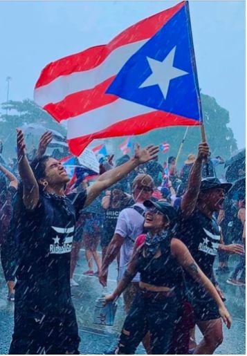 Puertorriqueños en la protesta verano 2019 bajo la lluvia bandera de PR